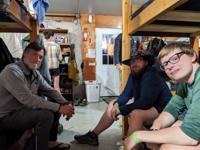 Three hikers sitting on bunk beds inside a hostel.